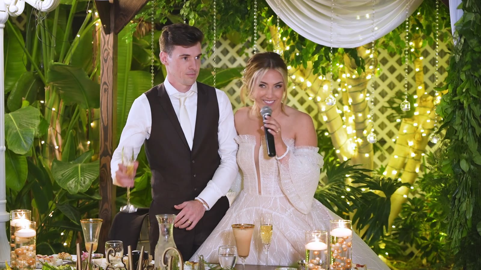 A couple at the head table in the garden lights